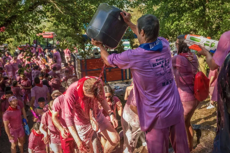 Miles de participantes vestidos empapados de vino tinto durante la Batalla del Vino de Haro en los Riscos de Bilibio, La Rioja.